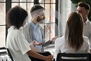 Serious man wearing glasses sharing problems at group therapy session