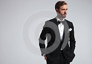 Serious man wearing tuxedo and standing with hands in pockets