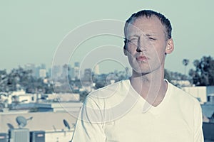 Serious Man in white T-shirt with Los Angeles sklyine