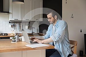 Serious man work distant on computer from home