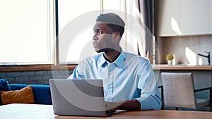 Serious man working on laptop computer at home office. Male typing on laptop keyboard