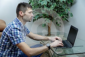 Serious man working at a laptop at home.