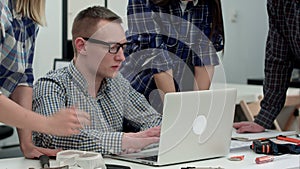 Serious manager in glasses looking at computer and talking to his team