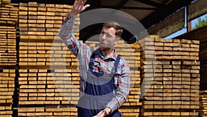 Serious manager in uniform giving commands to workers on lumber warehouse. Bearded man gesturing and shouting during