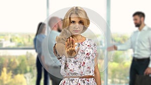 Serious mature blonde woman in office shows stop gesture sign with her hand.