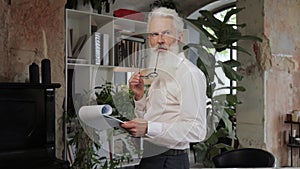 Serious mature business man in white shirt reading contract.