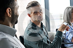 Serious mature ceo executive talking to African American manager in boardroom.