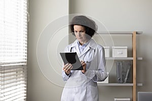 Serious mature female doctor using tablet computer