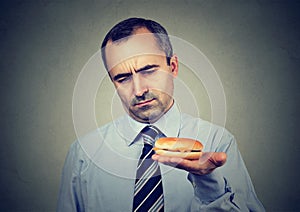 Serious mature man looking at cheeseburger