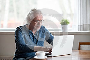 Serious mature man working on computer at home photo