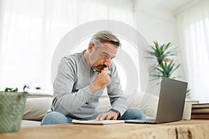 Serious mature man working on laptop