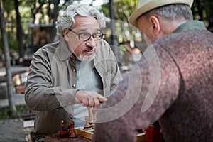 Serious mature men mulling over their strategy in chess game