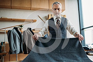 serious mature tailor with grey cloth