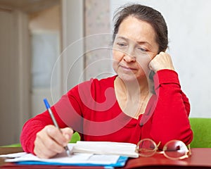 Serious mature woman fills in documents