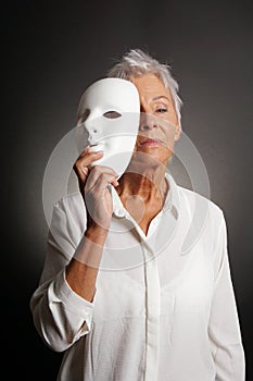 Serious mature woman revealing face behind mask