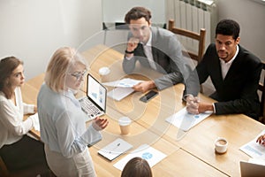 Serious mature woman team leader speaking at diverse team meetin