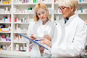 Serious mature and young female pharmacists working in the pharmacy