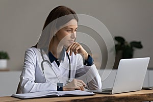 Serious medic professional, doctor, physician using laptop, giving online consultation