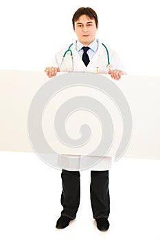 Serious medical doctor holding blank billboard