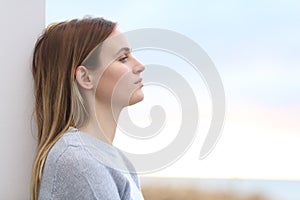 Serious melancholic woman looking away on the beach