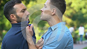 Serious men pushing each other outdoor, disagreement, start of fight, close-up