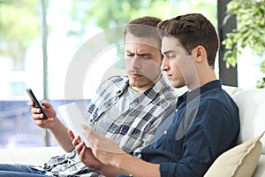 Serious men using tablet and phone at home