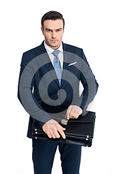 serious middle aged businessman holding briefcase and looking at camera