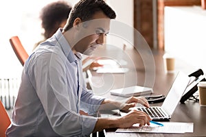 Serious middle-aged businessman working with laptop doing corporate paperwork