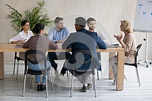 Serious middle aged businesswoman leading corporate meeting with diverse employees