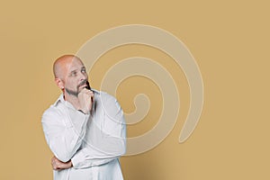 Serious middle-aged man with folded arms and a deadpan expression posing in front of a beige background with copy space