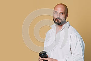 Serious middle-aged man with folded arms and a deadpan expression posing in front of a beige background with copy space