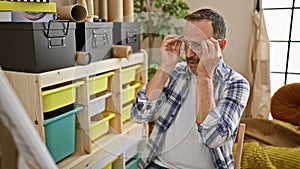 Serious middle-aged man with grey hair, doubting his art-school drawing. a bespectacled artist thinking in his studio