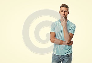 Serious middleaged caucasian guy in casual style keeping finger on chin isolated on white