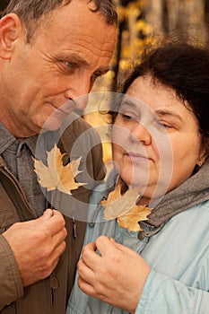 Serious middleaged man and woman hold maple leaves