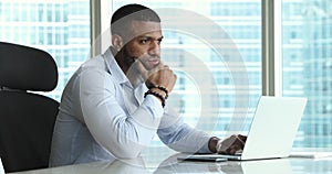 Serious millennial Black businessman working at laptop in office