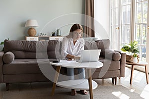 Serious millennial homeowner woman using online app on laptop