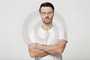 Serious millennial man in glasses posing with arms crossed