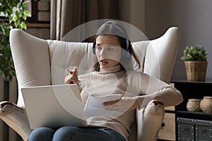Serious millennial student girl in wireless headphones talking to teacher