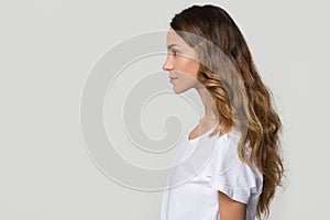 Serious millennial woman standing in profile on white grey background