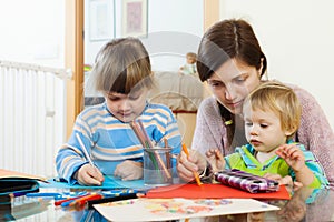 Serious mother and children sketching with pencils