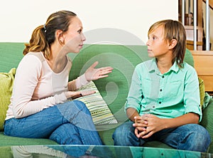 Serious mother and teen boy talking in home