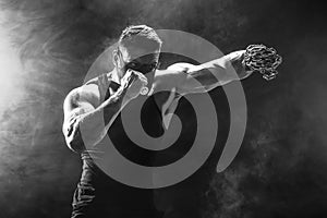 Serious muscular fighter doing the punch with the chains braided over his fist.