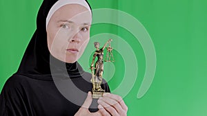 Serious muslim female in a black dress with a statue of Themis