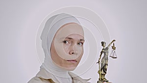 Serious muslim female with a statue of Themis