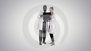 Serious nice woman doctor and afro american doctor study brain x ray on gradient background.