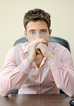 Serious office worker at his desk, looking at camera