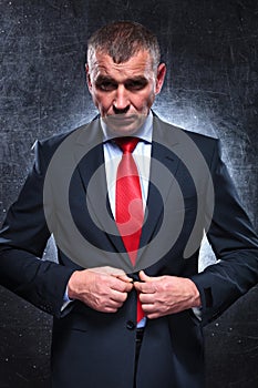 Serious old business man unbuttoning his suit
