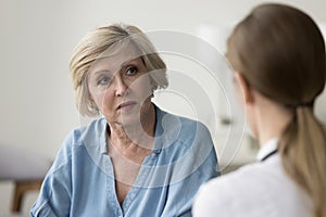Serious older patient woman visiting doctor, getting geriatric health problems