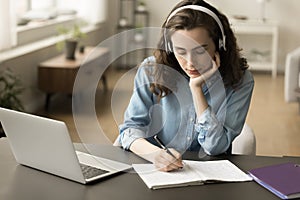 Serious online student girl in headphones listening to audio lesson