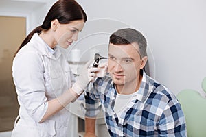 Serious otolaryngologist examining ear of male patient